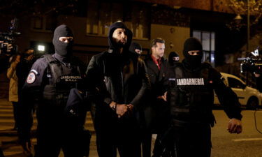 Andrew Tate and his brother Tristan Tate (background) are escorted by police officers in Bucharest on Thursday.