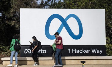 People walk by a sign on the Meta campus In Menlo Park