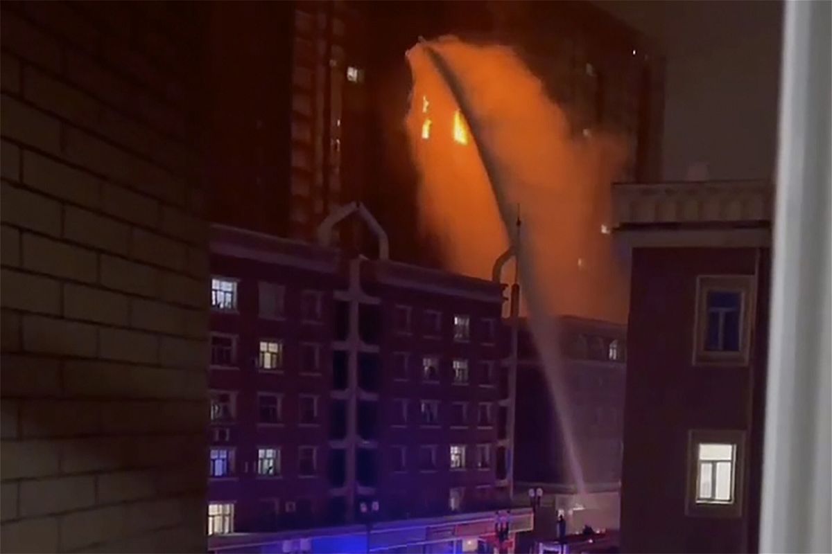 <i>AP</i><br/>Firefighters spray water on a fire at a residential building in Urumqi
