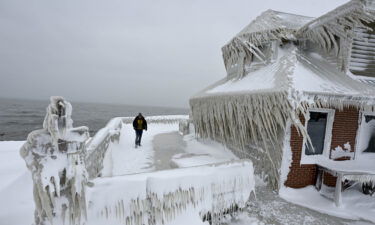 A man near a house completely covered in ice after snowfall in Buffalo