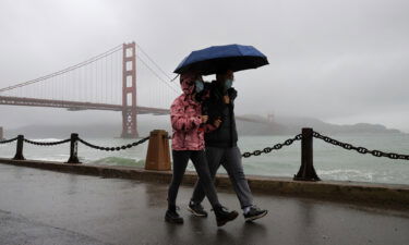 A couple walks near the Golden Gate Bridge as rain hits San Francisco this week.