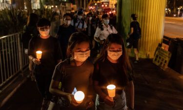 People hold candles as they walk near the Victoria Park on June 4