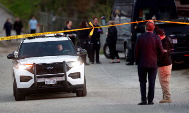 A San Mateo County deputy holds crime scene tape for a vehicle to pass by at a location near where multiple people were found shot to death Monday in Half Moon Bay