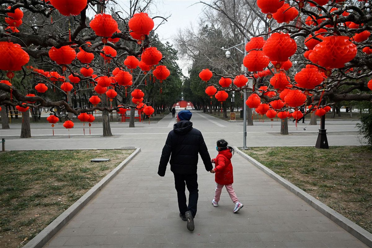 <i>Wang Zhao/AFP/Getty Images</i><br/>A man and a child pass red lanterns hanging on trees for the upcoming Lunar New Year celebrations at a park in Beijing