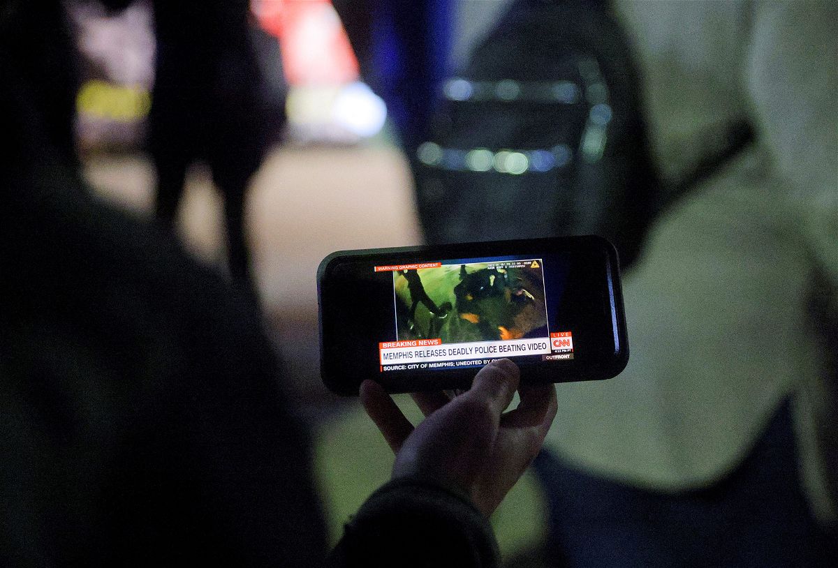 A protester watches a video of Memphis police beating Tyre Nichols.