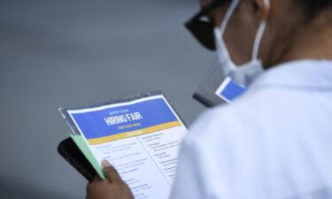 Unemployment among Latinos and Black women still hasn't recovered fully from the pandemic. A person reads a list of employers as they attend a job fair on September 9