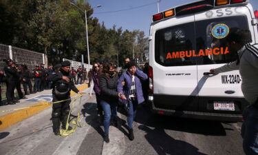 A woman is helped to reach an ambulance after two subway trains collided at a subway station in Mexico City on January 7.