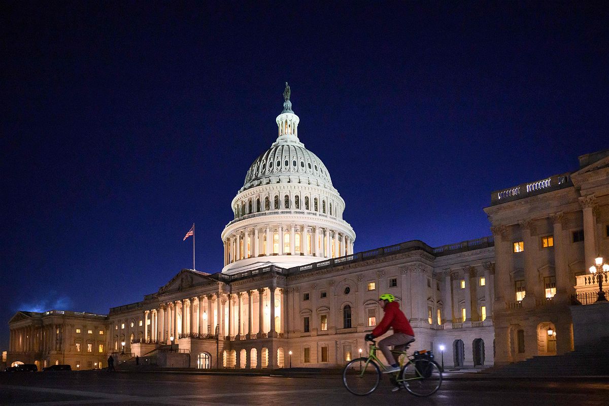 A cyclist drives past the US Capitol at dusk as the House of Representatives meets to vote on a set of rules for the 118th Congress.