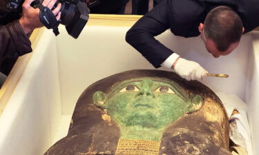 Mostafa Waziri of the Supreme Council of Antiquities takes a look with a magnifier at the ancient wooden sarcophagus during a handover ceremony at the foreign ministry in Cairo.