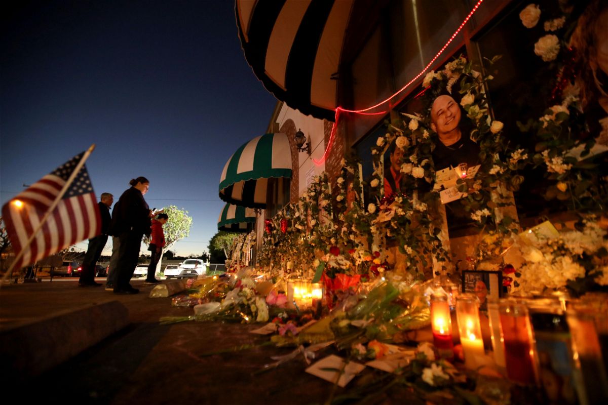 MONTEREY PARK, CA -  JANUARY 26, 2023 - - People pay their respects at the memorial for 11 people who died in a mass shooting during Lunar New Year celebrations outside the Star Ballroom Dance Studio in Monterey Park on January 26, 2023. (Genaro Molina / Los Angeles Times via Getty Images)