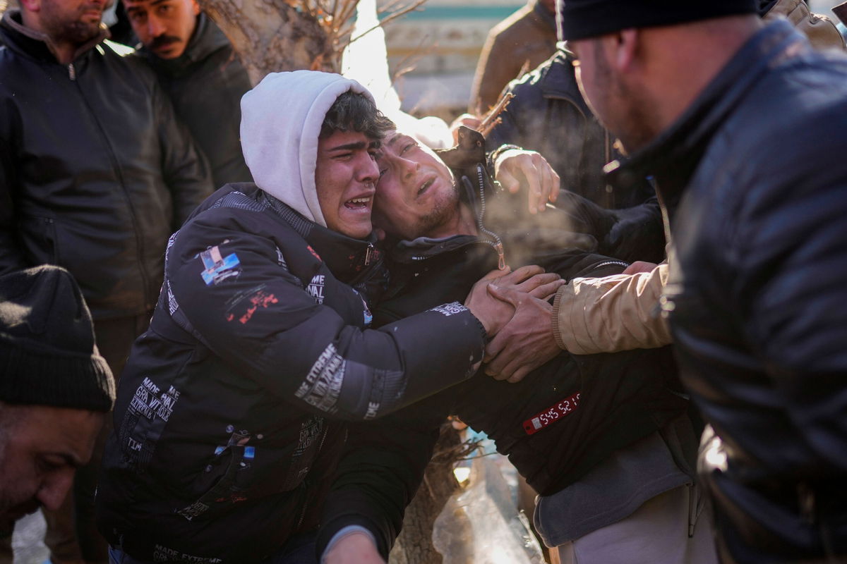 The son of Turkish Durmus Kilinc, center, reacts after rescue team members removed the dead body of his father from a destroyed building, in Elbistan, southeastern Turkey, Thursday, Feb. 9, 2023. Tens of thousands of people who lost their homes in a catastrophic earthquake huddled around campfires in the bitter cold and clamored for food and water Thursday, three days after the temblor hit Turkey and Syria. (AP Photo/Francisco Seco)