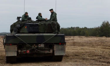 Ukrainian and Polish soldiers sit on top of a Leopard 2 tank at a military base in Swietoszow