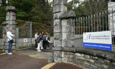 People stand at the entrance of the Saint-Thomas d'Aquin school in Saint-Jean-de-Luz