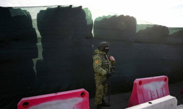 A Belarusian border guard keeps watch and stands by a barricade made of truck tyres at the Divin border crossing point between Belarus and Ukraine in the Brest region on February 15.