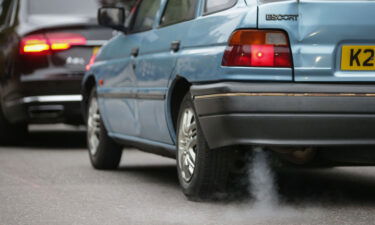 A car emits fumes from its exhaust as it waits in traffic in central London