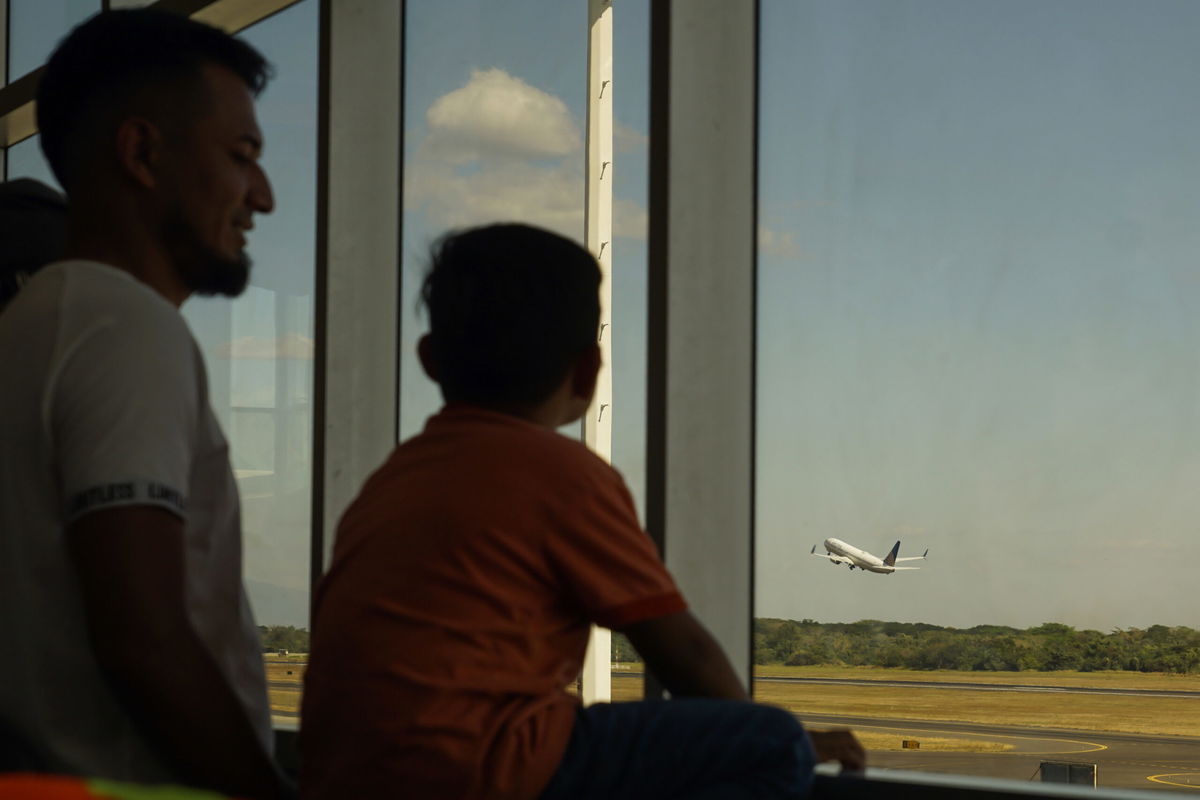 LA PAZ, EL SALVADOR - FEBRUARY 18: A man and his son watch a United Airlines plane take off from Comalapa International Airport on February 18, 2023 in La Paz, El Salvador. According to the Autonomous Executive Port Commission (CEPA), in 2022 more than 3.5 million visitors and passengers circulated through Comalapa International Airport, one of the most important and modern terminals in the Central American region, where 14 commercial and 6 cargo airlines operate. (Photo by APHOTOGRAFIA/Getty Images)