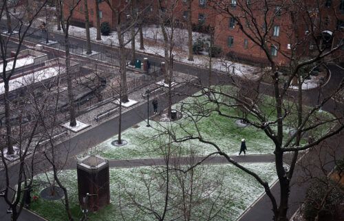 A person walks through a park following the first measurable snowfall of the season