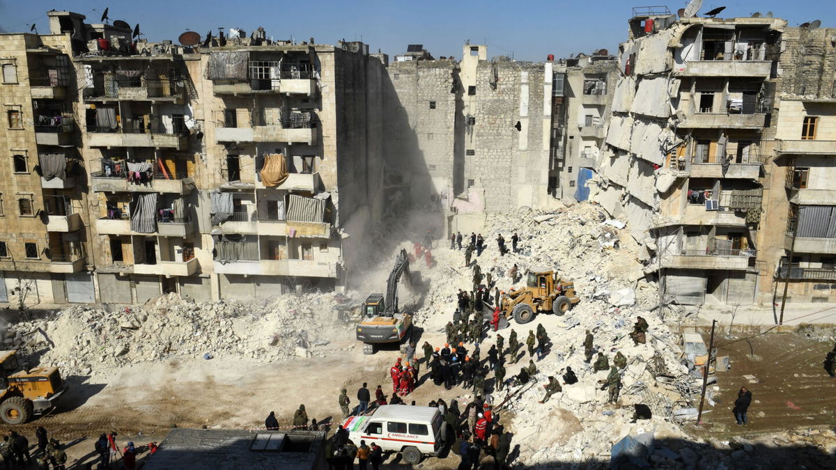 <i>AFP/Getty Images</i><br/>Syrian soldiers look on as rescuers use heavy machinery to sift through the rubble of a collapsed building in the northern city of Aleppo.