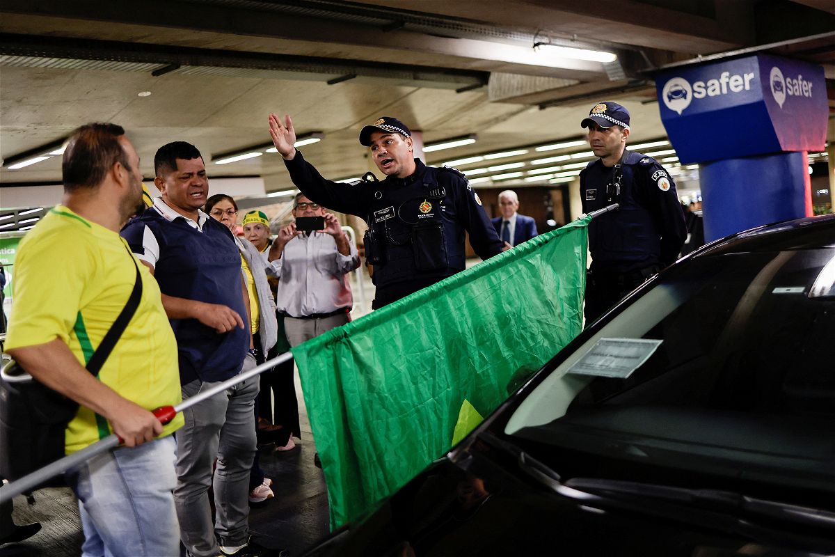 <i>Ueslei Marcelino/Reuters</i><br/>Bolsonaro supporters and members of the Brazilian security services at Brasilia airport on Thursday.