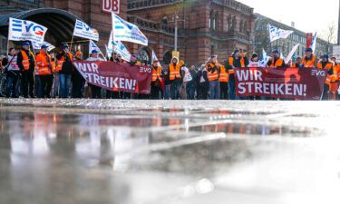 Demonstrators of the Railway and Transport Union stand with placards in front of the main train station in Bremen