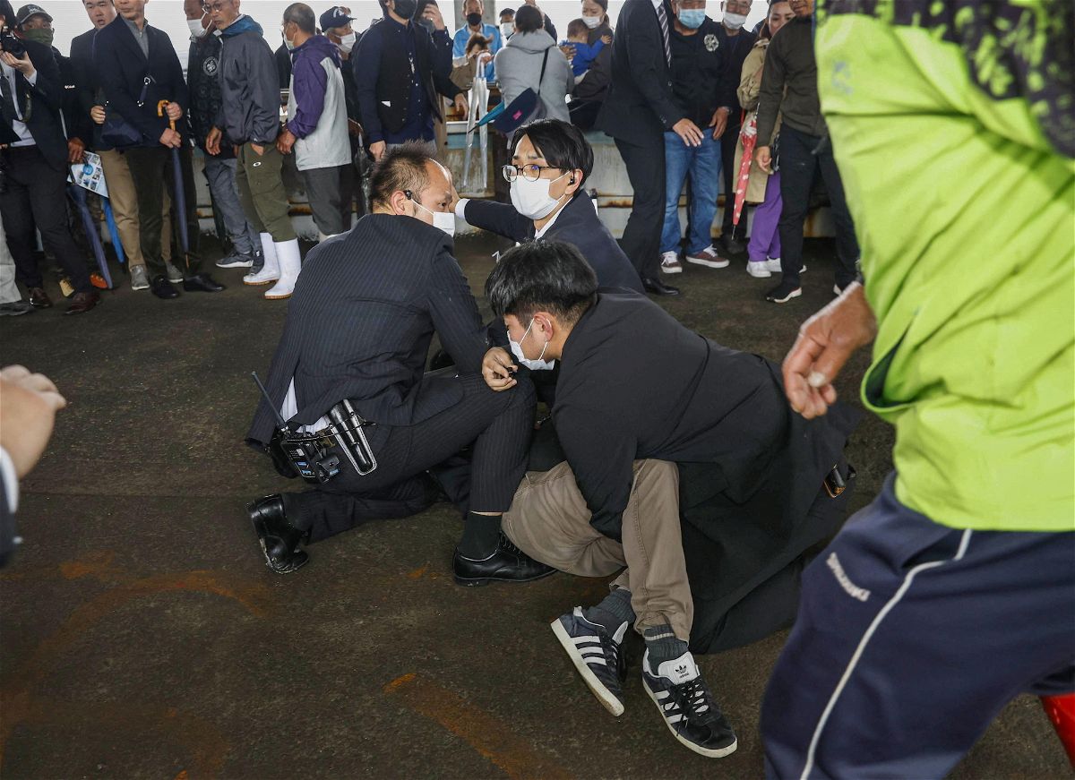 <i>Kyodo/Reuters</i><br/>A man is held by police officers after an object was thrown near Japanese Prime Minister Fumio Kishida during a speech in Wakayama