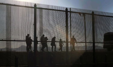 A US Border Patrol agent leads migrants who crossed into the US from Mexico to a van for transportation in El Paso