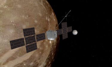 An artist's rendering depict Juice flying by Ganymede with Jupiter in the background.