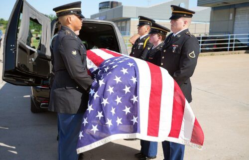 A military honor guard carries a casket containing the remains of World War II airman James M. Howie