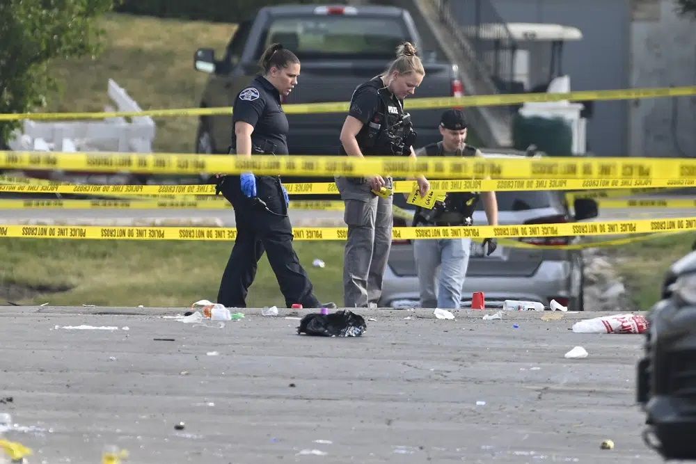 Investigators look over the scene of an overnight mass shooting at a strip mall in Willowbrook, Ill., Sunday, June 18, 2023
