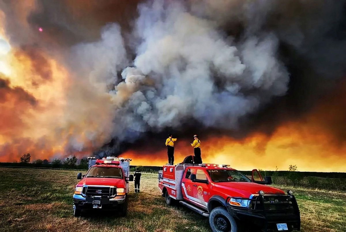 <i>Kamloops Fire Rescue via Reuters</i><br/>Firefighters stand on a Kamloops Fire Rescue truck at a wildfire near Fort St. John