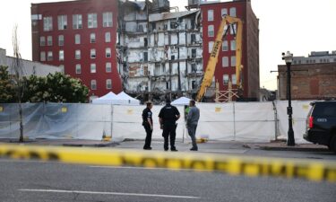 Officials stand near a six-story apartment building after a section of it collapsed in Davenport