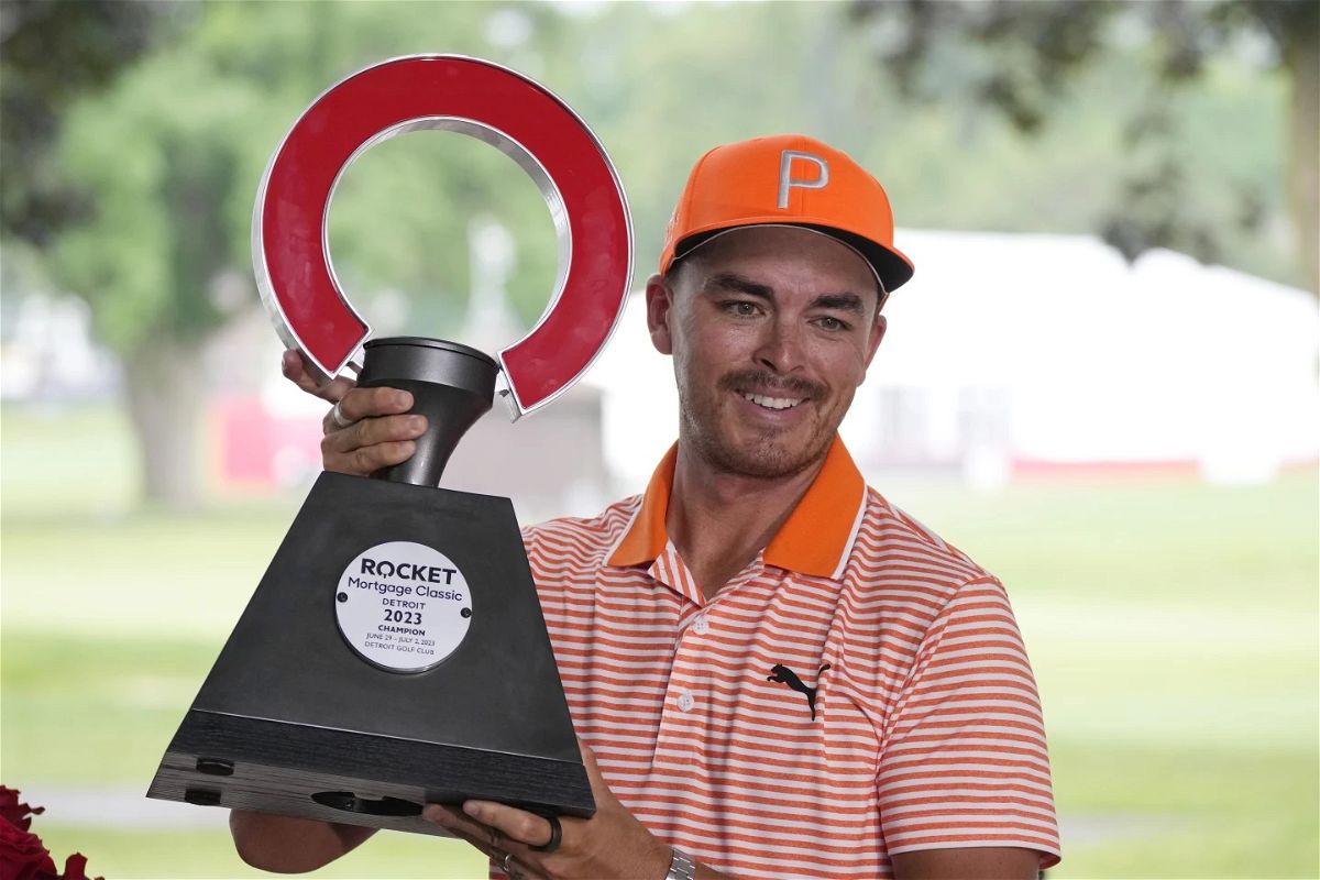 Rickie Fowler holds the winner's trophy after winning on the first play-off hole on the 18th green during the final round of the Rocket Mortgage Classic at Detroit