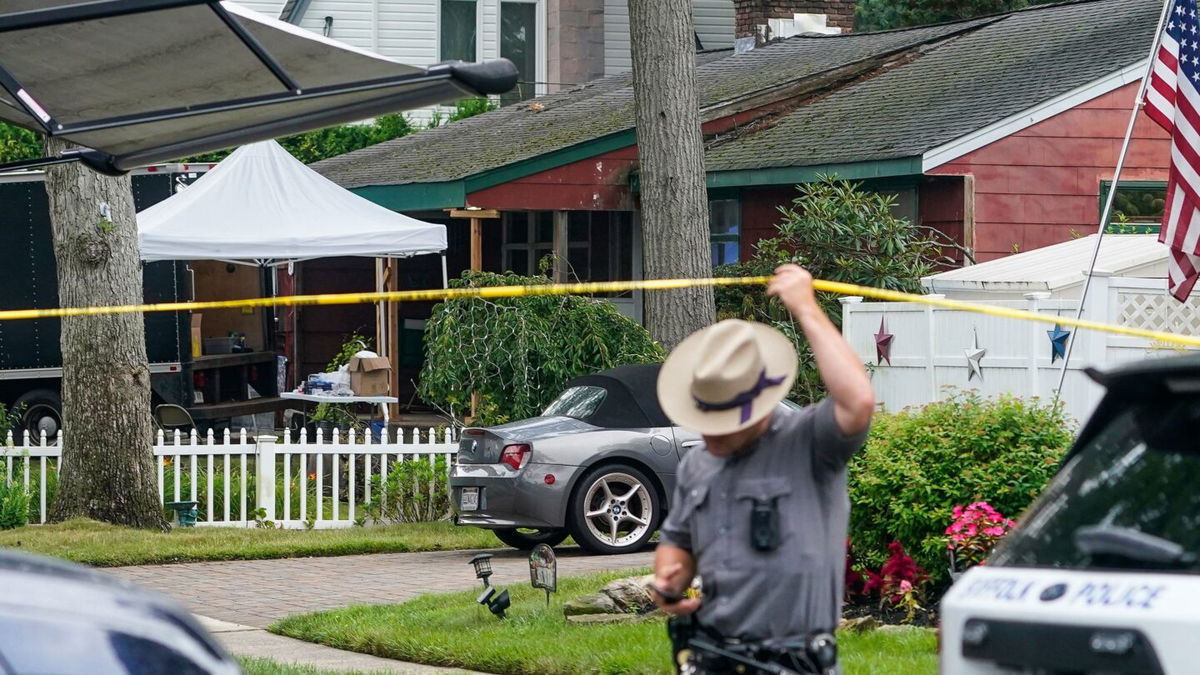 <i>John Minchillo/AP</i><br/>Authorities work outside as they search the home of suspect Rex Heuermann