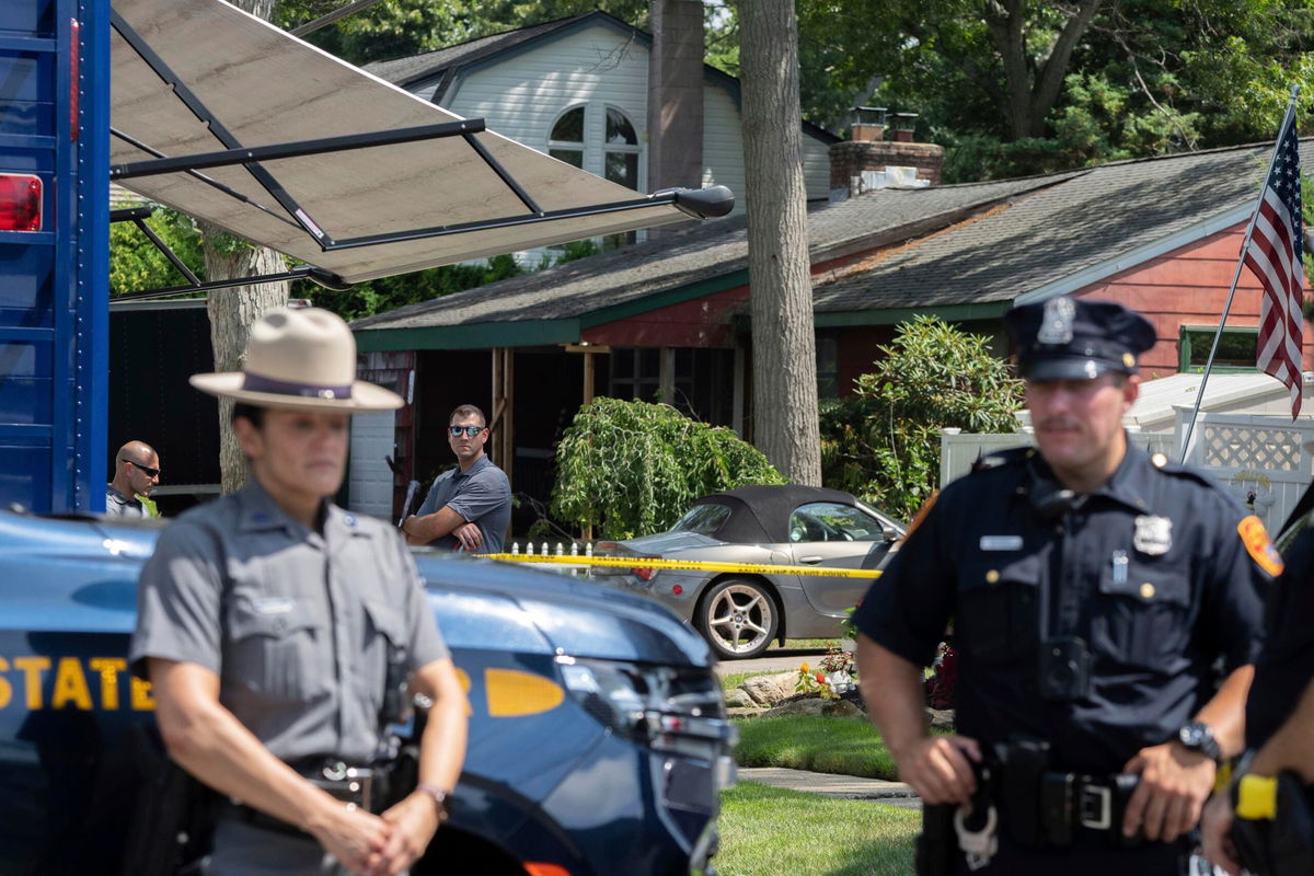 <i>Jeenah Moon/AP</i><br/>New York State police officers stand guard as law enforcement searches the home of Rex Heuermann