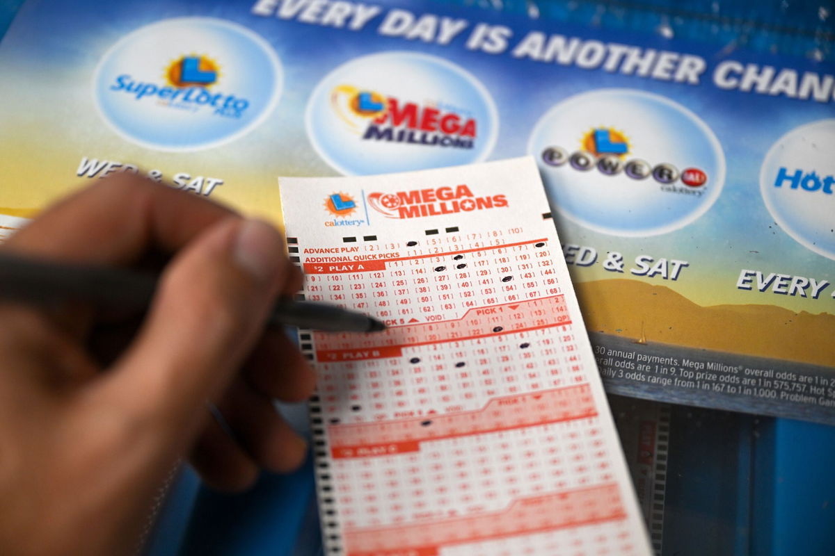 <i>Tayfun Coskun/Anadolu Agency/Getty Images</i><br/>A person plays Mega millions lottery at a gas station as giant Powerball and Mega Millions jackpots grow more than $1B combined