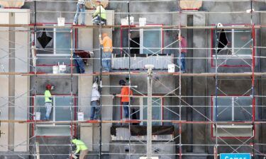 Construction workers stand on scaffolding while building residential housing on July 12 in Los Angeles