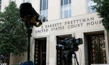 Television cameras are set up as people wait to enter E. Barrett Prettyman United States Courthouse on August 3