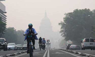 A cyclist rides under a blanket of haze partially obscuring the US Capitol in Washington