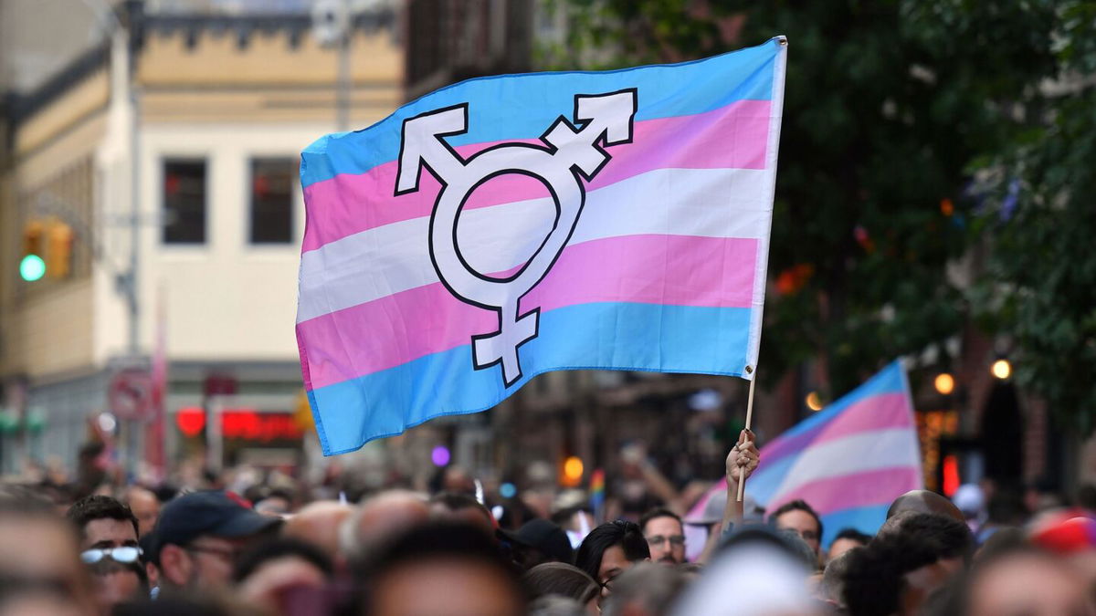 <i>Angela Weiss/AFP/Getty Images</i><br/>A person holds a transgender pride flag as people gather outside the Stonewall Inn in New York in June 2019. A study found that transgender and nonbinary patients have no regrets about top surgery.