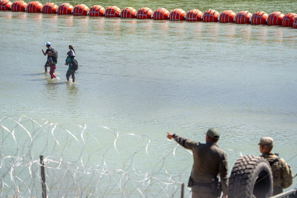 <i>Suzanne Cordeiro/AFP/Getty Images</i><br/>Texas Department of Public Safety highway patrol troopers look over the Rio Grande as migrants walk by a string of buoys placed on the water along the Rio Grande border with Mexico in Eagle Pass