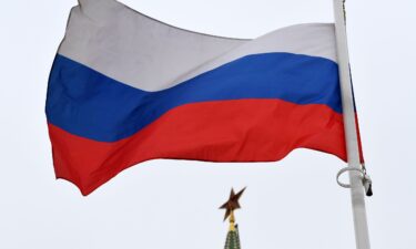 A Russian flag flies in front of a ruby star atop one of the Kremlin's towers in downtown Moscow.