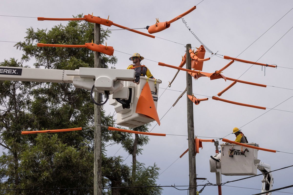 <i>Adrees Latif/Reuters</i><br/>Workers secure power lines ahead of a storm.