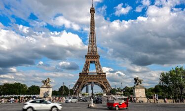 Cars drive past the Eiffel Tower in Paris on August 16