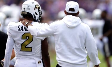 Shedeur Sanders and his father and head coach Deion Sanders walk the sidelines just before the game.