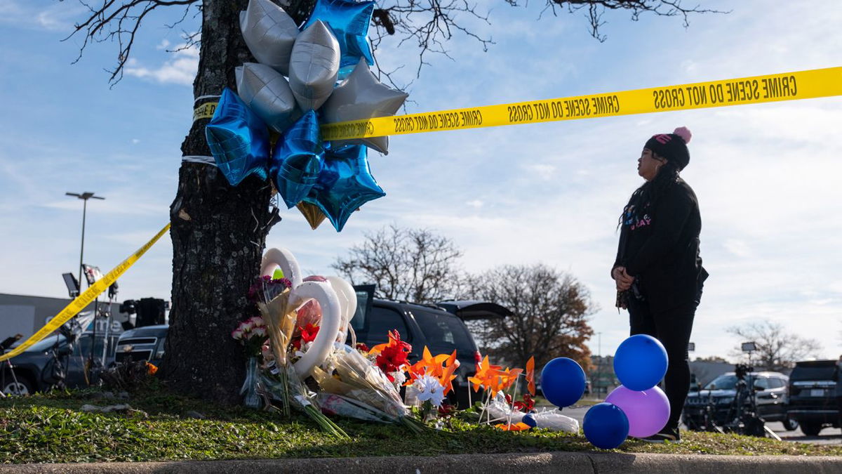 Mary Chatkovsky places balloons and flowers on a memorial outside of the Chesapeake, Virginia, Walmart in November 2022 after a manager opened fire on fellow employees in the break room of the store, killing six people.