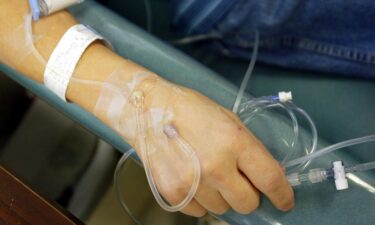 A cancer patient holds the IV tubes during chemotherapy. Some of the nation’s largest cancer centers are reporting little improvement in an ongoing shortage of critical chemotherapy drugs in the United States.