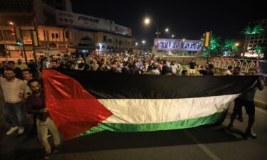 Protesters wave Palestinian flags while climbing the US embassy fence in Beirut