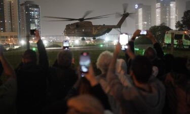 A group of Israelis watch as a helicopter carrying hostages released from Gaza lands at the helipad of the Schneider Children's Medical Center in Petah Tikva