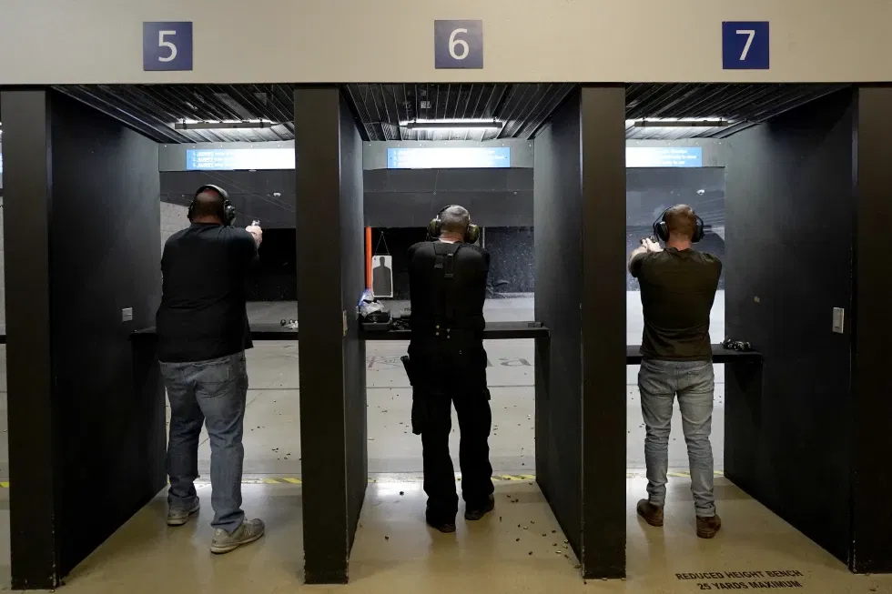 Gun owners fire their pistols at an indoor shooting range during a qualification course to renew their carry concealed handgun permits, July 1, 2022, at the Placer Sporting Club in Roseville, Calif. A California law that bans people from carrying firearms in most public places is taking effect on New Year’s Day, even as a court case continues to challenge the law.