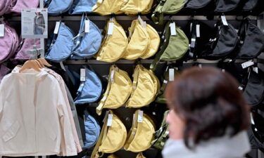 A woman walks past a rack of the viral Round Mini Shoulder Bag at a Uniqlo store in Tokyo